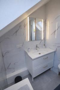 a white bathroom with a sink and a mirror at Maison spacieuse 8 pers 4 ch A31 EV in Rolampont