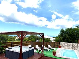 a deck with a hot tub and chairs and an umbrella at Villa Le Cyprès classée 4 Etoiles billard, piscine et jacuzzi in Saint-Joseph