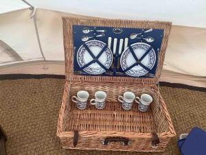 a basket with cups and utensils in a tent at Deer Barn Retreats in Hockworthy