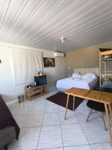 a bedroom with a bed and a desk and a table at Aconchego do Lar Hostel in Palhoça