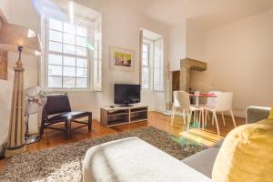 un soggiorno con TV e tavolo con sedie di São Mamede Downtown Apartment a Lisbona
