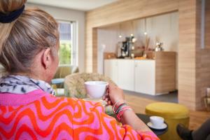 a woman sitting at a table with a cup of coffee at Bader Suites - Apartments in Garmisch-Partenkirchen