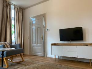 a living room with a flat screen tv on a white cabinet at Altstadtrefugium "Backsteenhuus" und ,,Li ebertee" in Leer in Leer