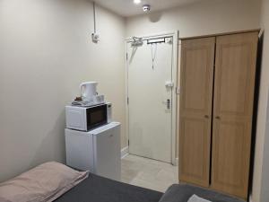 a bedroom with a microwave on top of a refrigerator at Romford Lodge in Romford