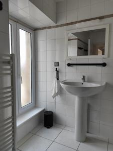 a white bathroom with a sink and a window at L'Orée du Puy in Les Herbiers