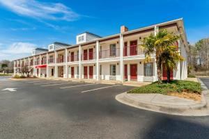 a large white building with red windows and a palm tree at Red Roof Inn & Suites Wilson in Wilson