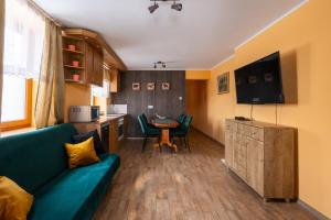 a living room with a green couch and a kitchen at Apartamenty Sawino 4 in Tykocin