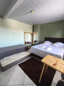 a bedroom with a bed and a wooden table at Aconchego do Lar Hostel in Palhoça