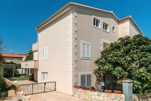 a white house with a tree in front of it at Villa Katina Supetar with private pool, pool table, barbecue in Supetar