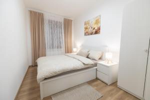 a white bedroom with a bed and a window at Apartman ''Kod bake'' Delnice biker-friendly in Delnice