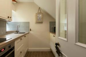 a kitchen with a sink and a clock on the wall at Sandpiper Alnmouth in Alnmouth +5 photos