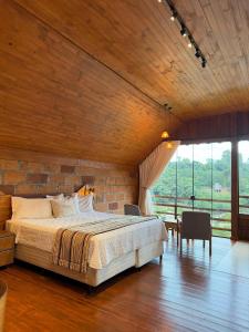 a bedroom with a large bed and a brick wall at Chalé Vicenza in Marques de Sousa