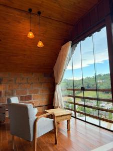 a room with a chair and a table and windows at Chalé Vicenza in Marques de Sousa
