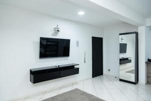 a living room with a tv on a white wall at Quitinete Moderna Centro Loft Studio Inteligente 5 in Presidente Prudente