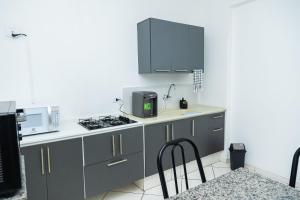 a kitchen with gray cabinets and a stove top oven at Quitinete Moderna Centro Loft Studio Inteligente 5 in Presidente Prudente