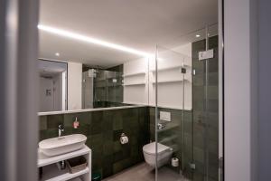 a bathroom with a toilet and a sink and a mirror at Residenza Pazzola in Disentis +21 photos