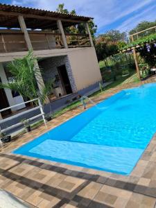 a blue swimming pool in front of a house at Chácara do Cardoso in Três Marias