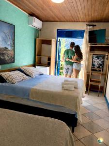 a man and woman standing in a bedroom with two beds at Pousada Recanto da Chapada in Mucugê