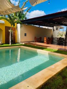 a swimming pool in front of a house with a patio at Hotel Villa Chucum in Valladolid
