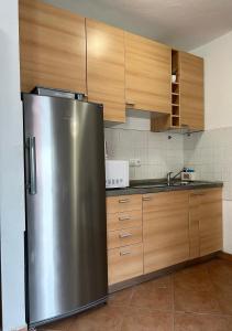 a stainless steel refrigerator in a kitchen with wooden cabinets at Apartment ADEPTO in Sveti Jakov