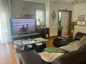 a living room with a couch and a flat screen tv at Grace House Quarto single privado in Belinho