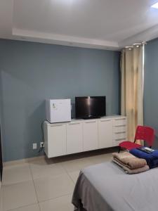 a bedroom with a tv and a bed and a red chair at Pousada Horbis in Guarabira
