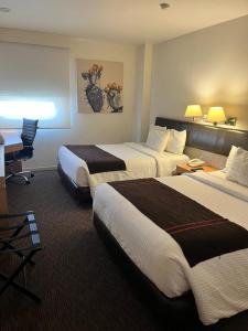 a hotel room with two beds and a desk at Hotel VM Express Queretaro in Mendiola
