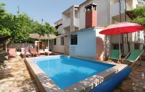 a pool with an umbrella and chairs and a house at Villa Katina Supetar with private pool, pool table, barbecue in Supetar