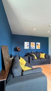 a living room with a couch and a blue wall at Au fil de vos nuits in Lustin