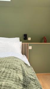 a bed with white sheets and a green blanket at Au fil de vos nuits in Lustin +7 photos