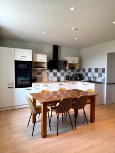 a kitchen with a wooden dining table and chairs at Au fil de vos nuits in Lustin