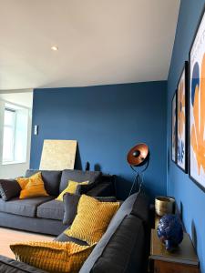 a living room with blue walls and a couch at Au fil de vos nuits in Lustin