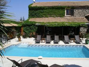 une piscine avec des chaises et un bâtiment dans l'établissement La Bergerie Du Cap, au Cap d'Agde