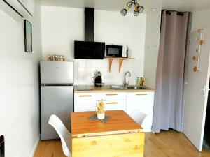 a small kitchen with a wooden table and a refrigerator at L'instant voyageur in Virsac