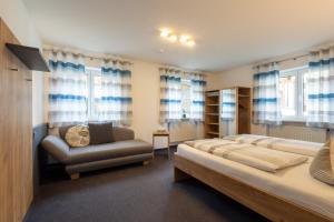 a bedroom with a bed and a couch and windows at Gästehaus Sonner in Dietmannsried
