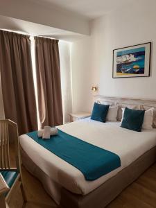 a bedroom with a large bed with blue pillows at Hotel Bonaparte in Bastia