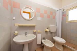 a bathroom with a sink and a toilet and a mirror at Villaggio Turistico Grotta dell'Acqua in Peschici