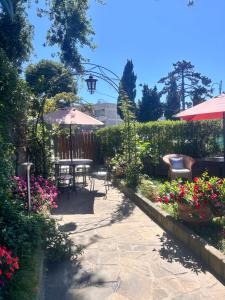 a patio with flowers and tables and an umbrella at Maison Villa Angela in SantʼAgata sui Due Golfi