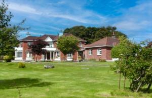a large brick house with a green yard at Whitaker Lodge in Swinford