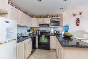 a kitchen with white cabinets and black appliances at Unique Colorful Condo on 3rd Floor Pinacate 321 in Puerto Peñasco