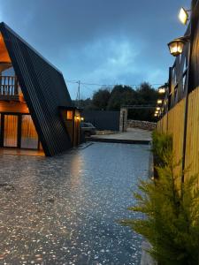 a house with a stone driveway with a black roof at أكواخ غصُن عجلون in Ajloun