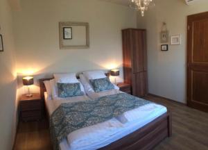 a bedroom with a large bed and two lamps at Vass-Villa Vendégház in Szekszárd