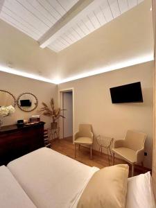 a bedroom with a bed and two chairs and a television at Camilla Garden in Pisa