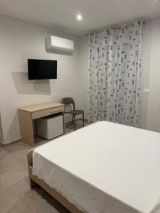 a bedroom with a bed and a desk and a television at Sofia s Rooms in Falcone