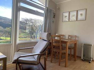a living room with a table and a chair and a window at 49 Erw Porthor in Tywyn