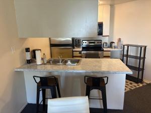 a kitchen with a sink and a counter with stools at Steps from UCLA Westwood 1 Bd 1Ba in Los Angeles +11 photos