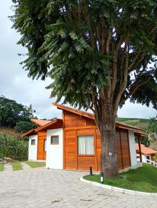 a house with a tree in front of it at Chalés da Preguiça in Pedra Menina