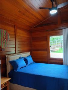 a bedroom with a bed with blue pillows and a window at Chalés da Preguiça in Pedra Menina