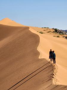 three people walking down a sand dune at Hamada Kem-Kem Tafraoute in Tafraoute Sidi Ali