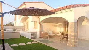 a patio with an umbrella and a table and chairs at Villa 21 in Budoni